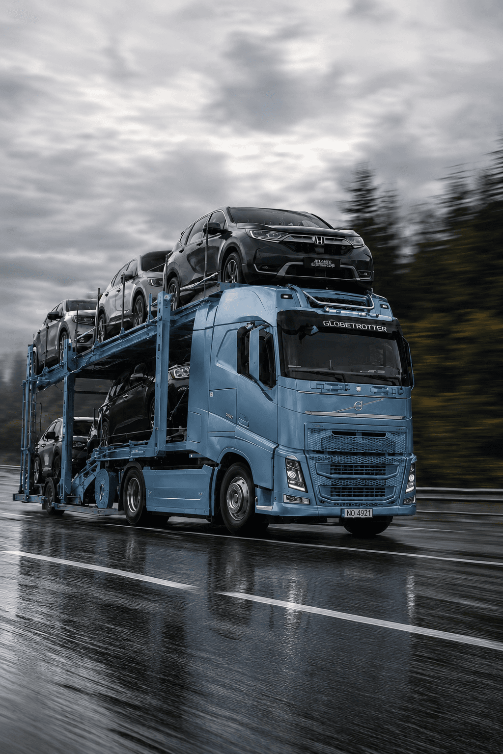 Автовоз Volvo FH із легковими авто на мокрій трасі